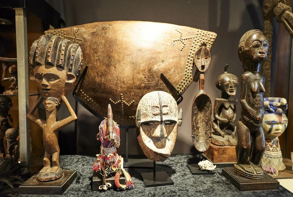 Een masker en beeld gecombineerd, een kinderpop met kraaltjes, een misvormd masker, een trommel en veel meer antieke Afrikaanse kunst is te vinden in de winkel. — © Jeroen Hanselaer